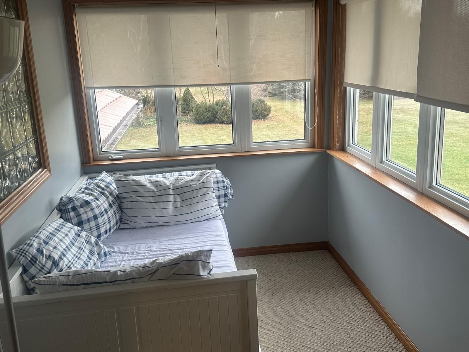 A corner bedroom with a window seat, a radiator, and a view of the outdoors.