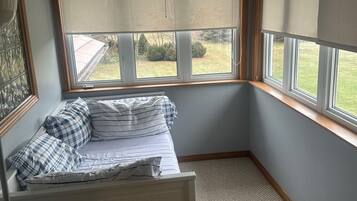 A corner bedroom with a window seat, a radiator, and a view of the outdoors.