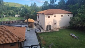 A white building with a tiled roof, a small wooden structure, and a grassy yard. - FARM WITH 7 CHALETS PERFECT FOR THAT FAMILY MOMENT (Santa Isabel)