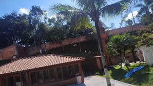 A building with a tiled roof and large windows, surrounded by greenery and a swimming pool. - FARM WITH 7 CHALETS PERFECT FOR THAT FAMILY MOMENT (Santa Isabel)
