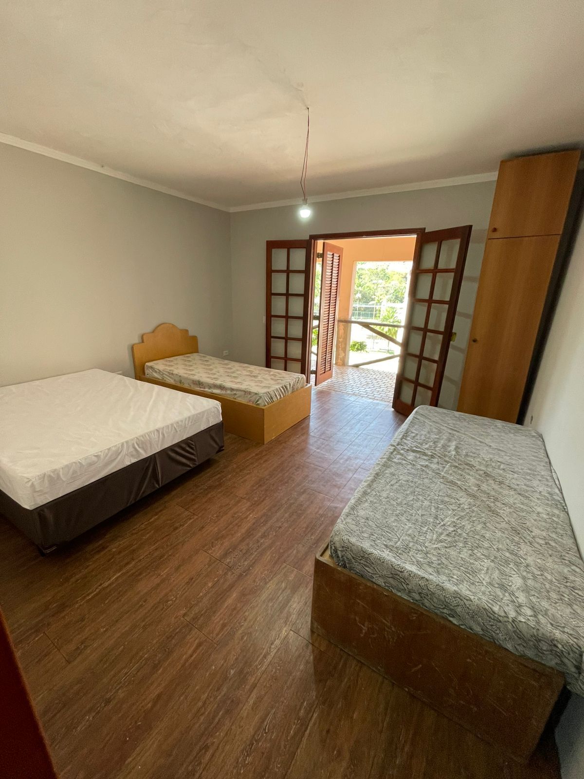 Una habitación con dos camas individuales, suelo de madera, un armario y una puerta que da al exterior.