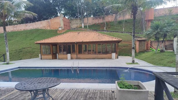 A swimming pool with a wooden deck, a covered seating area, and a palm tree in the background. - FARM WITH 7 CHALETS PERFECT FOR THAT FAMILY MOMENT (Santa Isabel)