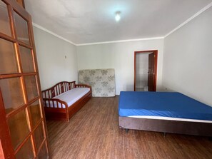 A room with a wooden floor, a bed with a blue mattress, a wooden headboard, and a window with a wooden frame. - FARM WITH 7 CHALETS PERFECT FOR THAT FAMILY MOMENT (Santa Isabel)