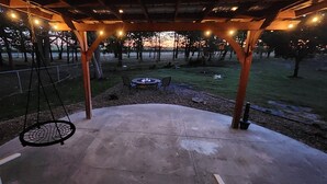 A covered outdoor area with a swing, a fire pit, and string lights. - Prairie Refuge/EV Charger (Deerfield)