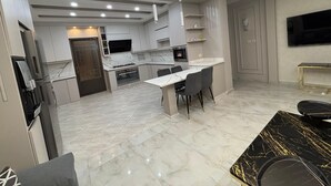 A modern kitchen with a dining area, built-in appliances, and a flat-screen TV. - 3-bedroom apartment in lovely Amman with AC (Amman)