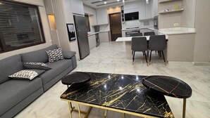 A modern kitchen with a dining area, a sofa, and a table. - 3-bedroom apartment in lovely Amman with AC (Amman)