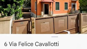 A multi-story building with a red facade, multiple windows, and a gated entrance. - B&B Cavallotti (Mestre)