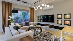 A modern living room with a sofa, coffee table, and TV. - ALSAWAH Spacious Garden Apartment in 9th District Sheikh Zayed (Sheikh Zayed City)