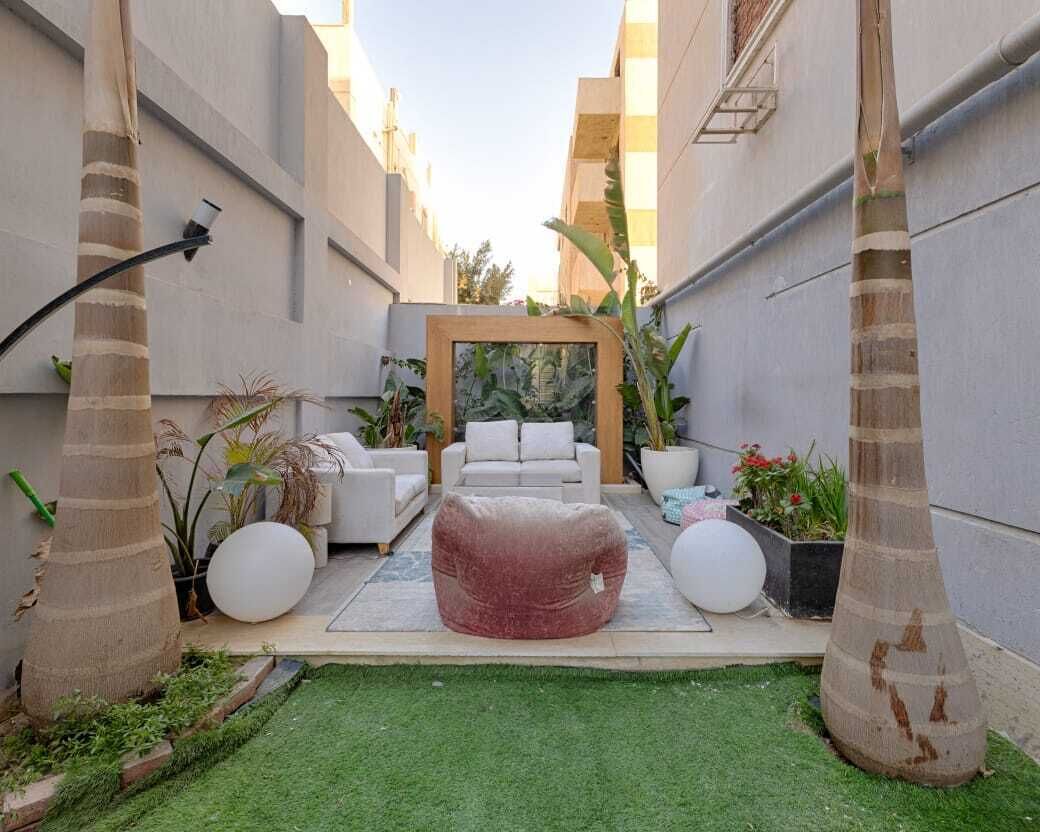 Eine moderne Außenpatio mit einer weißen Couch, einem roten Sitzsack und einer Holzbogenkonstruktion.