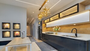 A modern kitchen with a wooden countertop, black cabinets, and a built-in oven. - ALSAWAH Spacious Garden Apartment in 9th District Sheikh Zayed (Sheikh Zayed City)