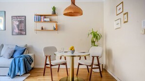 A modern living room with a round dining table, two chairs, a sofa, a bookshelf, and a hanging pendant light. - The Best Apartment in Stylish Sodermalm Stockholm (Stockholm)