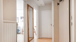 A hallway with a wooden floor, white walls, and a large mirror. - The Best Apartment in Stylish Sodermalm Stockholm (Stockholm)