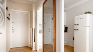 A modern kitchen with a white refrigerator, wooden flooring, and a white door with a keyhole. - The Best Apartment in Stylish Sodermalm Stockholm (Stockholm)