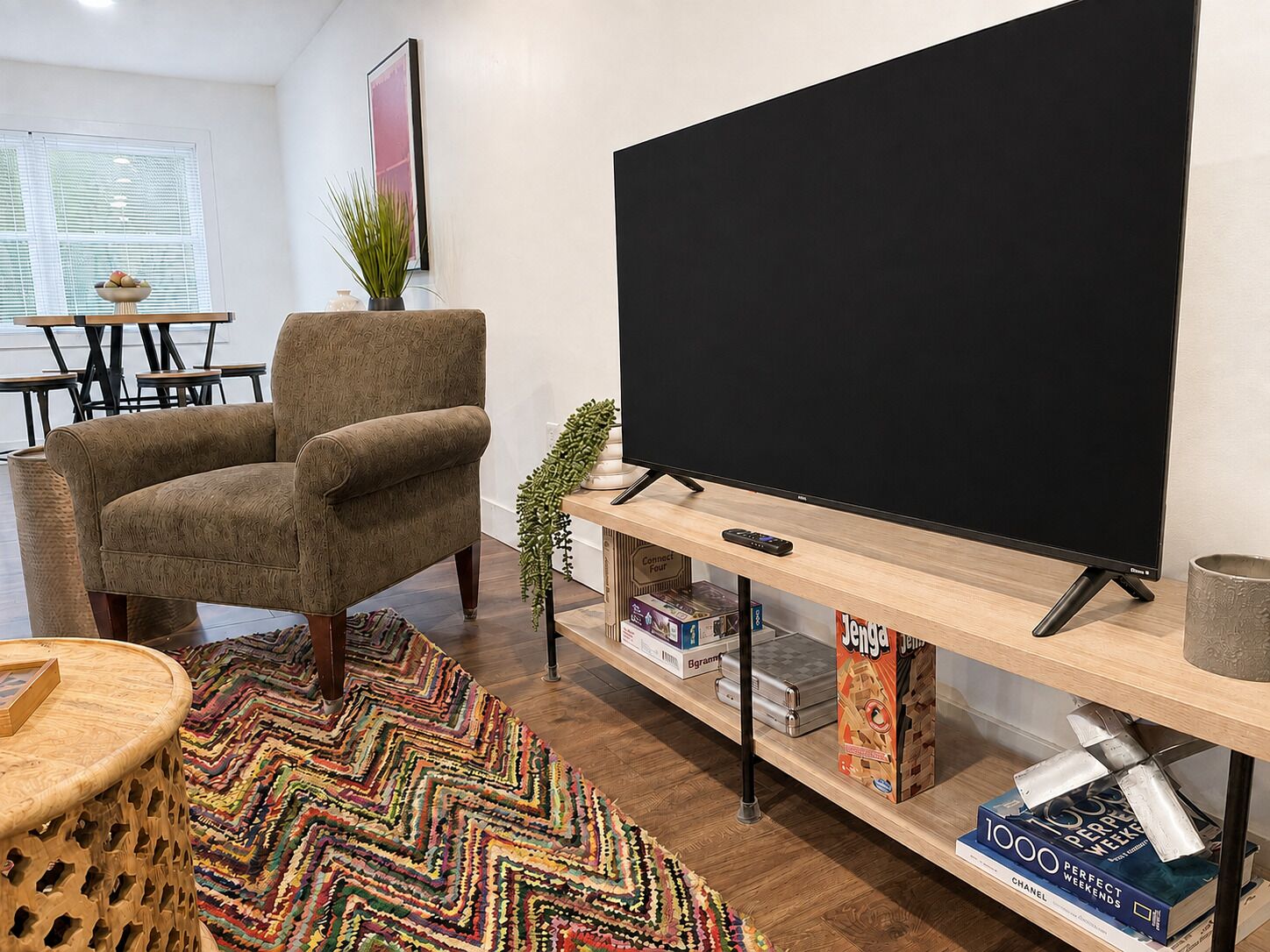 A living room with a television, a sofa, a coffee table, and a bookshelf with books and games.