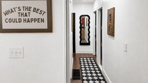 A hallway with a framed inspirational quote, a decorative mirror, and a patterned rug. - Your Cortland Base Near SUNY (Cortland)