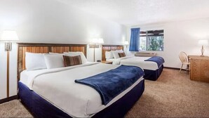 A hotel room with two beds, a desk, and a window with curtains.