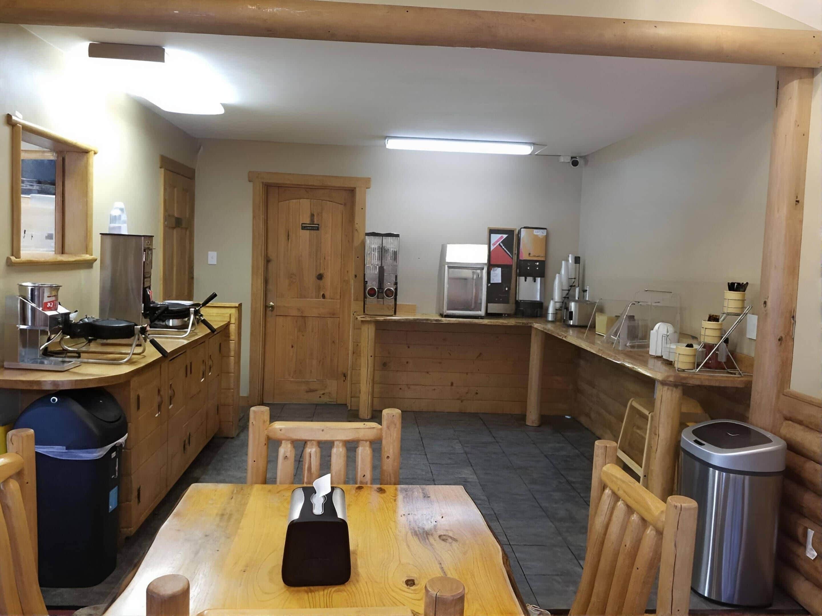 Una cocina compacta con armarios de madera, una cafetera y un cubo de basura.