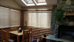 A cozy room with a wooden table and chairs, a stone fireplace, and a skylight.