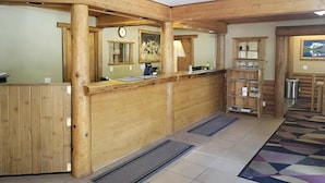 A reception area with a wooden reception desk, a clock, a painting, and a patterned rug.