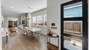 Un espace repas moderne avec une table en bois, des chaises blanches et un luminaire central.