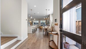 Une cuisine spacieuse équipée d’appareils modernes, un coin repas avec une grande table et une vue sur l’extérieur grâce à une porte vitrée.