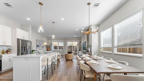 Une cuisine moderne avec des meubles blancs, un îlot central et un coin repas doté d’une longue table pouvant accueillir six personnes.