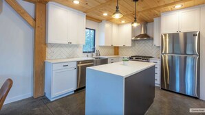 Une cuisine moderne avec des meubles blancs, un réfrigérateur en acier inoxydable et un îlot central.