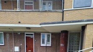 Ein Gebäude mit Backsteinfassade, Holztür und Fenster mit weißem Rahmen.