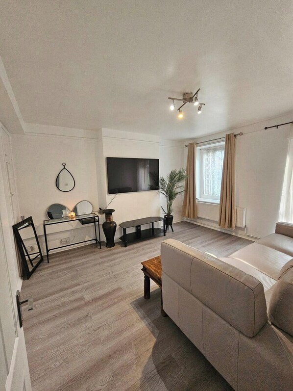 Een moderne woonkamer met een bank, een salontafel, een televisie en een bijzettafeltje.