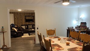 Comedor con mesa dispuesta para seis comensales, sillas de madera y un ventilador de techo.