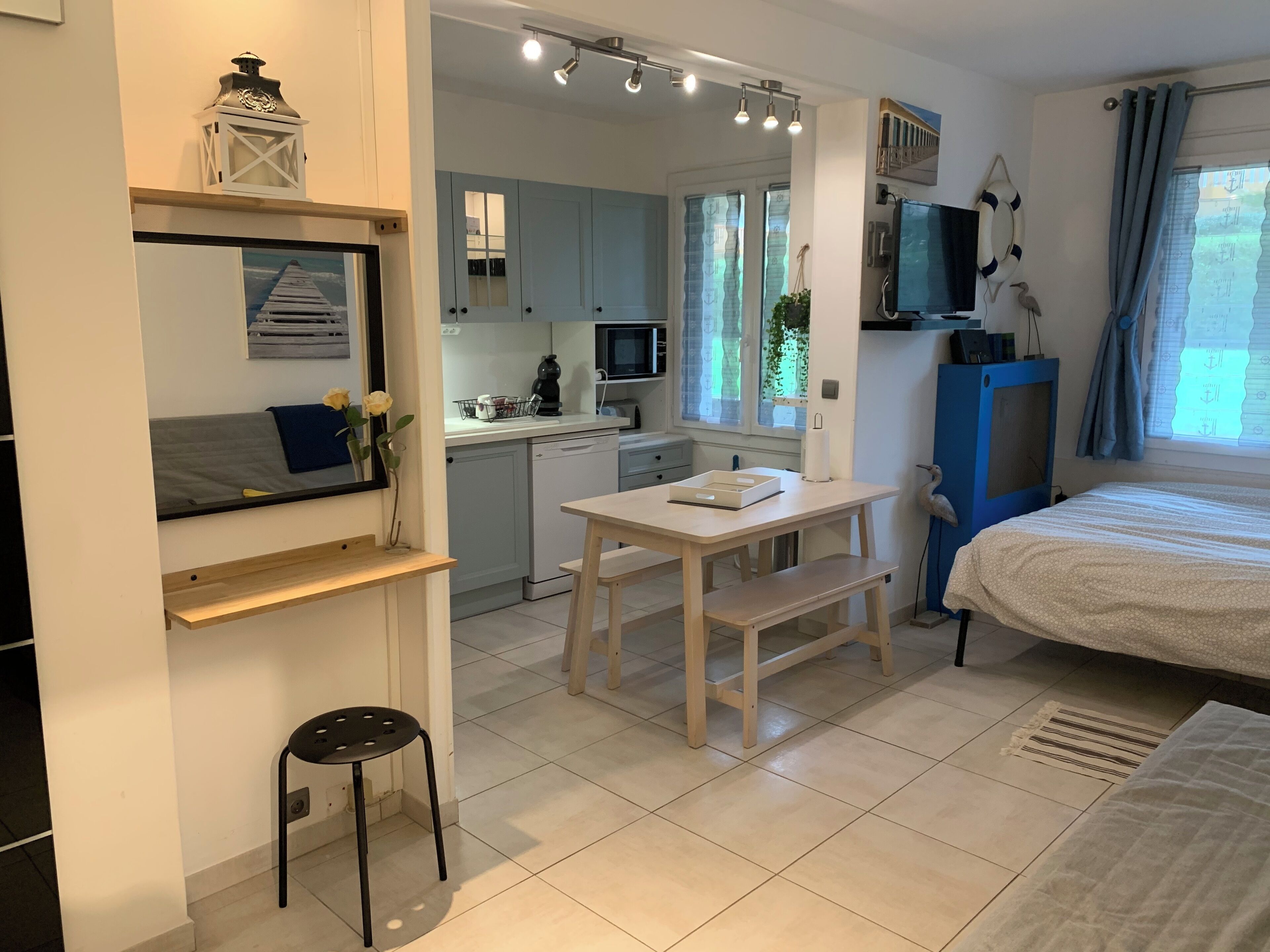 A compact, well-lit room with a bed, a desk, and a kitchenette.