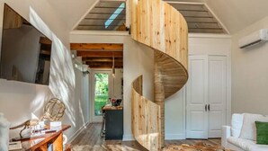 Ein modernes Interieur mit einer Wendeltreppe, Holzboden und einer Mischung verschiedener Möbel.
