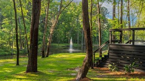 Eine Holzterrasse mit Treppe zu einem Gazebo mit Blick auf einen Teich und einen Springbrunnen.