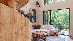 Ein geräumiger Wohnbereich mit einer Holztreppe, einem großen Fenster mit Blick ins Freie und einer modernen Leuchte.