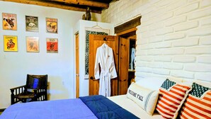 A bedroom with a bed, a chair, a robe, and a wall with posters.