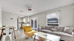 Een moderne woonkamer met een bank, salontafel en eethoek.
