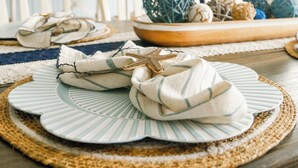 A dining table with striped placemats, a starfish decoration, and a bowl of colorful balls. - Beachside Family Getaway Nestled in the Woods at Fort Morgan, AL (Gulf Shores)
