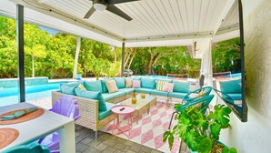 Un espacio exterior cubierto con piscina, sofá modular y mesa de comedor.