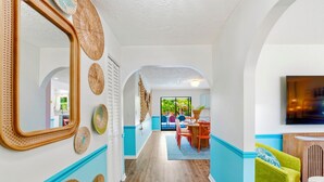 Un pasillo con suelo de madera, paredes azules y blancas, y una zona de comedor con mesa y sillas.