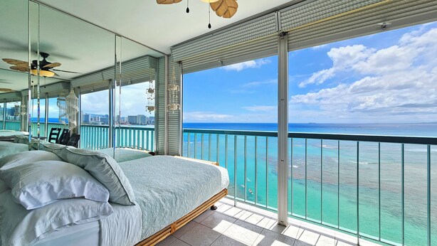 Ein Schlafzimmer mit einem großen Bett, einem Deckenventilator und Meerblick.