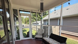 A covered patio with a red floor, a black bench, and a patterned chair. - 3-bedroom bungalow, centrally located in charming Saint Joseph (Saint Joseph)