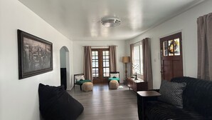 A spacious living room with a large window, a sofa, a chair, and a small table. - 3-bedroom bungalow, centrally located in charming Saint Joseph (Saint Joseph)