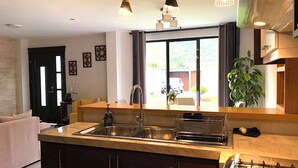 Une cuisine moderne dotée d’un îlot central, d’appareils électroménagers en acier inoxydable et de luminaires suspendus.