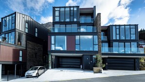 Un bâtiment moderne à deux étages, doté de grandes fenêtres, d’un garage et d’une voiture garée devant.