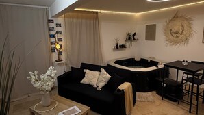 Ett modernt vardagsrum med en svart soffa, ett träbord och en liten matplats med ett bord och stolar.