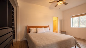 Une chambre à coucher avec un lit, une tête de lit en bois et un ventilateur de plafond.