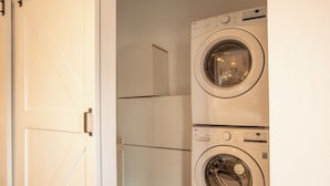 Un espace buanderie avec deux machines à laver superposées et un meuble blanc.
