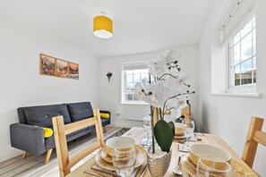 Un salon moderne avec un coin repas, comprenant un canapé, une table à manger et une plante orchidée.