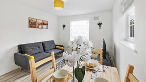 A modern living room with a grey sofa, wooden coffee table, and a yellow pendant light. - 4 Min to LTN | Modern Stylish | WiFi | FreeParking (Luton)