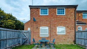 A brick house with a patio, a wooden fence, and a satellite dish. - 4 Min to LTN | Modern Stylish | WiFi | FreeParking (Luton)